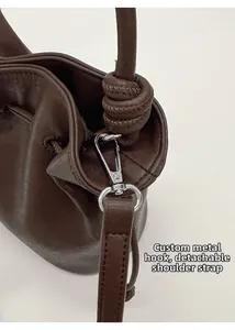 Détail du crochet en métal argenté et de la bandoulière en cuir amovible du sac seau brun