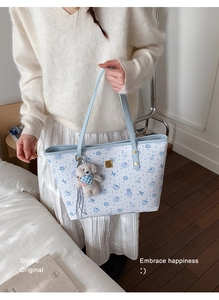 Detail of light blue quilted tote bag with cartoon patterns and plush dog charm
