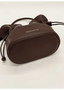Détail de la base ovale structurée de ce sac seau en cuir marron foncé