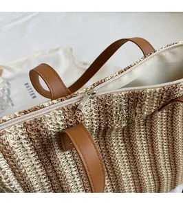 Detail of smooth silver zipper and woven texture on beige straw tote bag