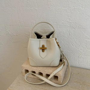 Detail of cream pebbled leather bucket bag with gold T-shaped clasp on stone pedestal