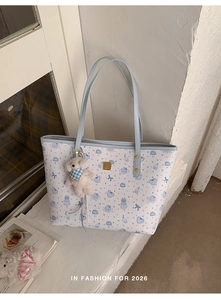 Detail of white and blue tote bag with cartoon bear patterns and plush bear charm