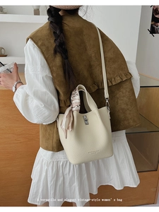Detail of cream lychee texture bucket bag with silver twist lock and floral scarf handle