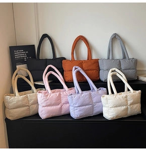 Multiple colors of quilted puffer tote bags displayed on a sleek black platform