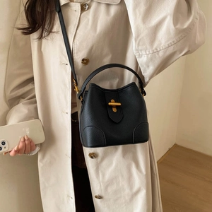 Detail of black lychee leather bucket bag featuring a striking gold metal toggle closure