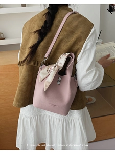 Detailed view of pink pebble leather bucket bag with decorative scarf and silver metal clasp