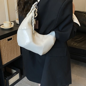 Dettaglio della borsa hobo bianca con tracolla intrecciata e cuciture minimaliste