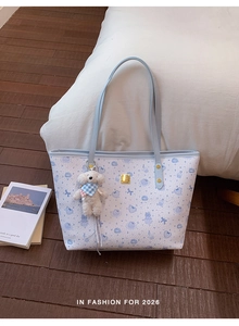 Detail of printed tote bag with light blue leather straps and cute puppy charm