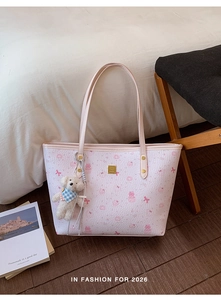 Detail of pink tote bag featuring cartoon bunny prints and a plush bear charm accessory