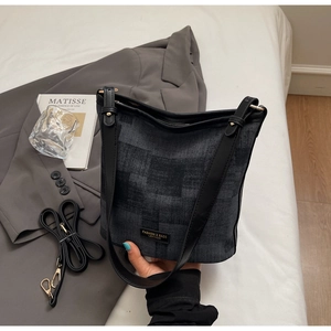 Dettaglio della borsa a secchiello in denim grigio con finiture in pelle