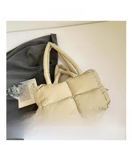 Detailed close-up of beige quilted tote bag with soft padded handles and puffer texture