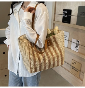 Détail du sac cabas rayé en paille avec bandoulières en cuir marron et texture tissée
