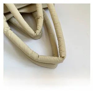 Close-up of padded top handle on a beige quilted bag with high-quality soft stitching