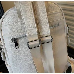 Detail view of adjustable leather straps and secure rear zipper pocket on beige backpack