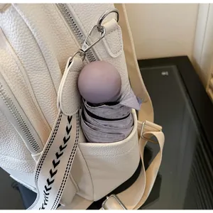 Detail of white lychee leather backpack side pocket holding a purple folding umbrella