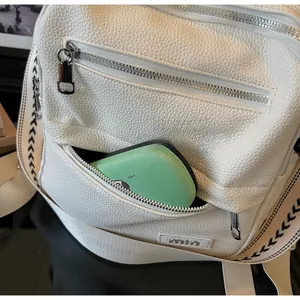 Detail of white lychee leather backpack with metal logo and geometric woven shoulder strap