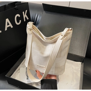 Dettaglio borsa a secchiello off-white con trama twill e logo in metallo in scatola