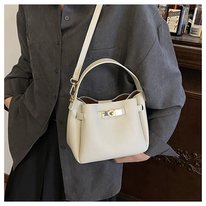 Gros plan du sac seau en cuir crème avec texture grainée et détails métalliques dorés
