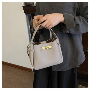Détail du sac seau en cuir grainé gris clair avec un fermoir rotatif doré élégant