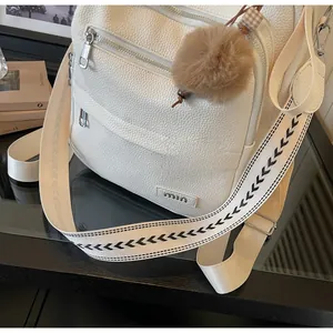 Detail of white lychee leather backpack with multi-zipper pockets and patterned strap