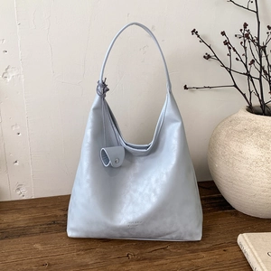 Dettaglio della borsa tote in morbida pelle azzurra con piccolo portamonete su legno scuro