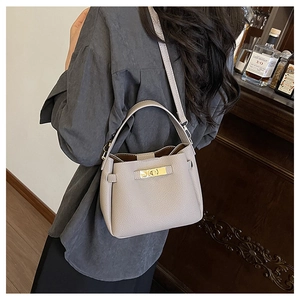 Sac seau gris clair en cuir grainé porté par un mannequin pour un look élégant et chic