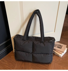 Close-up of black quilted puffer tote bag showing soft texture and large capacity