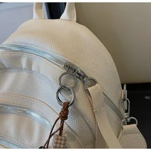 Macro view of white lychee leather texture and silver ring zipper on the backpack