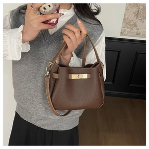 Détail du sac seau en cuir marron foncé avec fermoir doré et bandoulière réglable