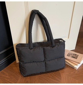 Macro view of black quilted puffer tote bag with durable padded straps and secure zipper