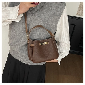 Détail du cuir à grain litchi et du fermoir doré sur un sac à main marron vintage