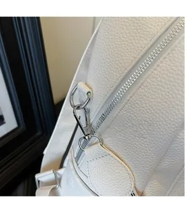 Macro detail of white lychee leather texture and silver hardware on a versatile backpack