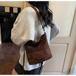 Vista dettagliata di una borsa a secchiello marrone a motivi portata a spalla in interni