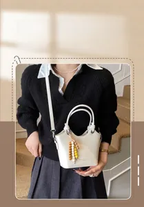 Detail of cream bucket bag with leather texture and colorful wooden bead charm