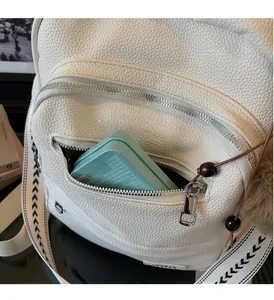 Detailed shot of white lychee leather backpack with metal zipper and woven strap