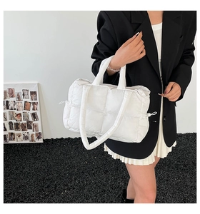 Detail of white quilted tote bag texture and drawstring closure on soft nylon fabric