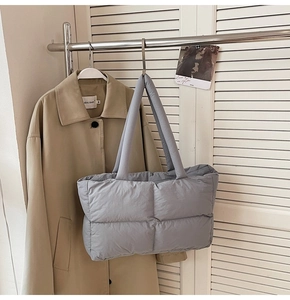 Close-up of gray quilted puffer tote bag with thick handles and padded texture