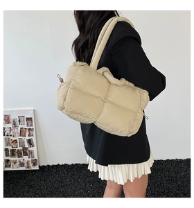 Detailed close-up of beige quilted puffy tote bag texture and soft drawstring side detail