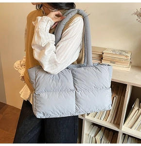 Detail of grey puffer tote bag showing quilted nylon texture and wide padded shoulder strap