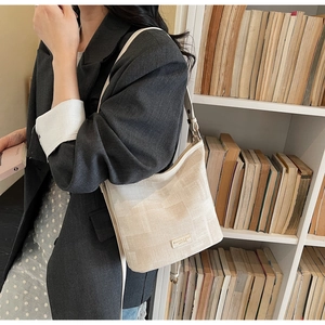 Dettaglio borsa a secchiello strutturata bianco crema con patch logo e sottile tracolla