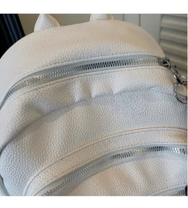 Detail of white lychee grain leather backpack featuring silver zippers and cute cat ear decor