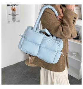 Detail of light blue quilted shoulder bag with soft padding and square stitching
