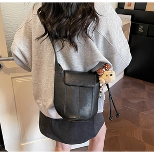 Detail einer schwarzen Eimer-Tasche aus Kieselleder mit süßem Plüschbär-Anhänger-Zubehör