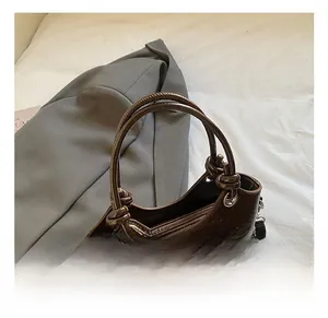 Detail einer dunkelbraunen Handtasche aus Ölwachsleder mit Silberschnalle und Perlenanhänger