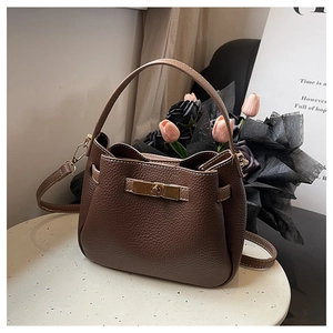Détail d'un sac seau en cuir grainé marron foncé avec fermoir rotatif en métal doré