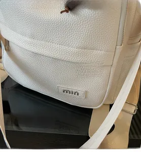 Close-up of white pebble leather backpack featuring silver min logo and zipper detail