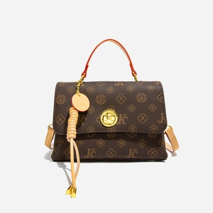 Close-up of vintage brown patterned crossbody bag with gold lock and leather tassel