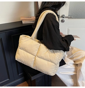 Macro detail of cream quilted puffer tote bag showing glossy nylon fabric and stitching