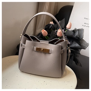 Détail de sac seau en cuir gris à motif litchi avec fermoir tournant en métal doré