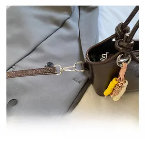 Detail der dunkelbraunen Glanz-Eimertasche mit Silberhaken und bunten Perlen